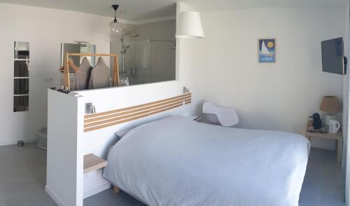 a white bedroom with a bed and a mirror at Les Suites du XV in Cap d'Agde