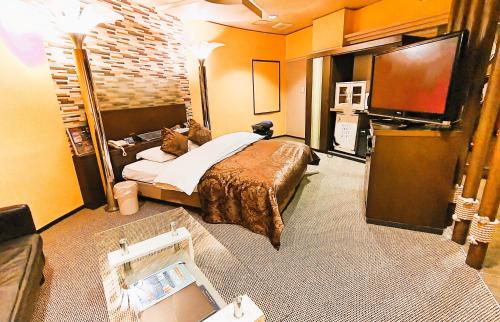 um quarto de hotel com uma cama e uma televisão de ecrã plano em Surfrider Adult Only em Sendai