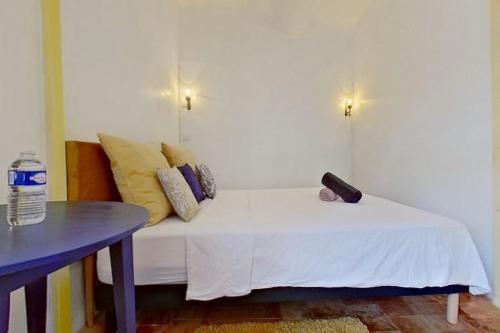 a white bed in a room with a table at Les 2 Drôles d'Oiseaux in Luc-sur-Orbieu