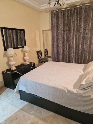 um quarto com uma cama, 2 candeeiros e uma janela em Spacieux appartement au centre-ville de Tanger em Tânger