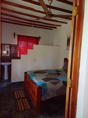 a bedroom with a bed and a ceiling fan at Karibu Paradaizi in Michamvi