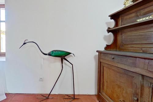 a green bird standing in a room next to a wall at Les 2 Drôles d'Oiseaux in Luc-sur-Orbieu
