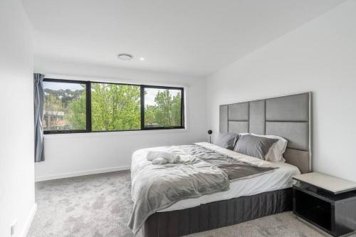 ein weißes Schlafzimmer mit einem großen Bett und einem Fenster in der Unterkunft O‘Connor 3 bedroom Townhouse in Canberra in Canberra