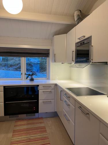 Håkøyveien 151, Tromsø في ترومسو: مطبخ فيه دواليب بيضاء واجهزة سوداء