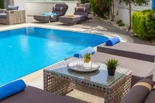 a swimming pool with a table and chairs next to it at Fig Tree Bay Residences 3 in Protaras