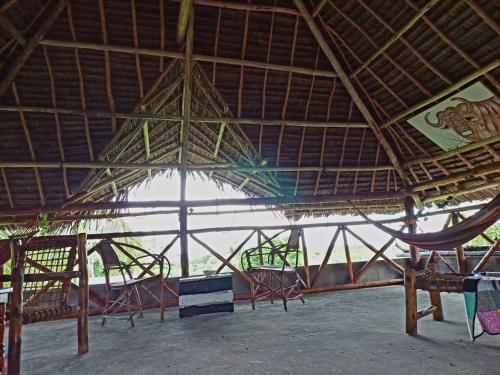 a large straw roofed building with chairs and a hammock at Karibu Paradaizi in Michamvi