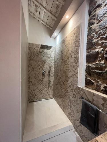 a bathroom with a shower with a stone wall at B&B Salaju in Castelsardo