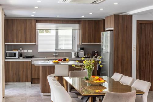 a kitchen with a glass table with chairs and a counter at Fig Tree Bay Residences 3 in Protaras