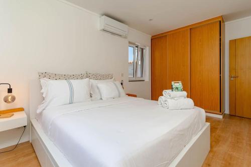 um quarto branco com uma grande cama branca e uma secretária em Caparica Dream Vila em Costa da Caparica