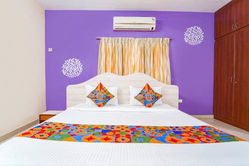 1 dormitorio con 1 cama blanca grande y paredes moradas en FabExpress Shree Shylee Niwas, en Chennai