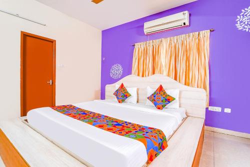 2 camas en una habitación con paredes moradas en FabExpress Shree Shylee Niwas, en Chennai