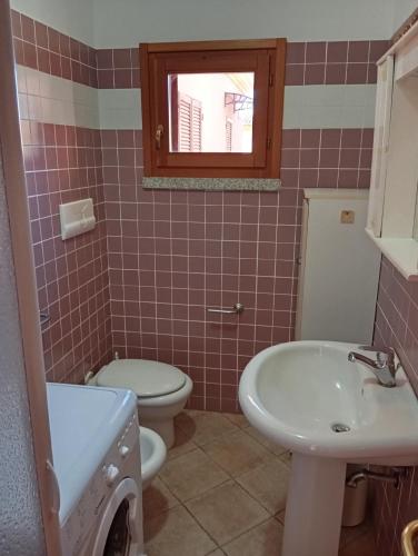 a bathroom with a sink and a toilet and a window at A.I.R. Isola Rossa Borgo di Mare in Isola Rossa