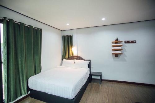 a bedroom with a white bed and a green curtain at Green Country Park Resort in Ban Tha Mak