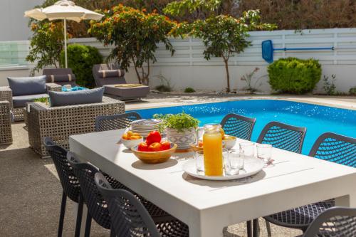 a table with fruit and juice next to a pool at Fig Tree Bay Residences 3 in Protaras
