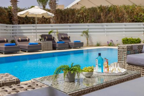 a pool with chairs and a table with drinks on it at Fig Tree Bay Residences 3 in Protaras
