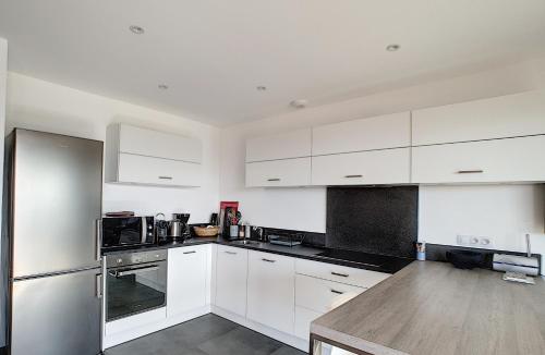 une cuisine avec des armoires blanches et un réfrigérateur en acier inoxydable dans l'établissement APPARTEMENT PORTICCIO, à Porticcio