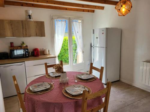 une cuisine avec une table et un réfrigérateur dans l'établissement Maison de plage Le cocon Pirouais, à Pirou