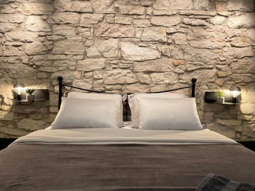a bed with two pillows in front of a stone wall at Apartment Golden Gate in Pula
