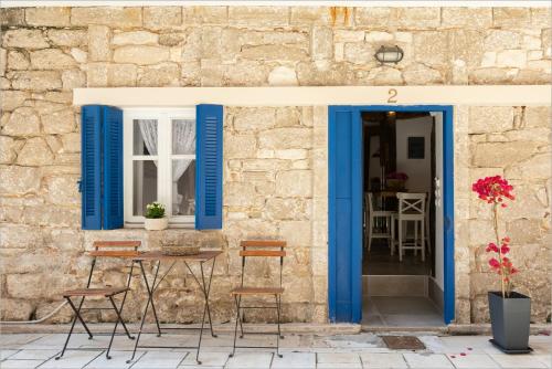 a table and chairs in front of a building with blue shutters at Ziv Boutique Apartments Town Square in Lefkada Town
