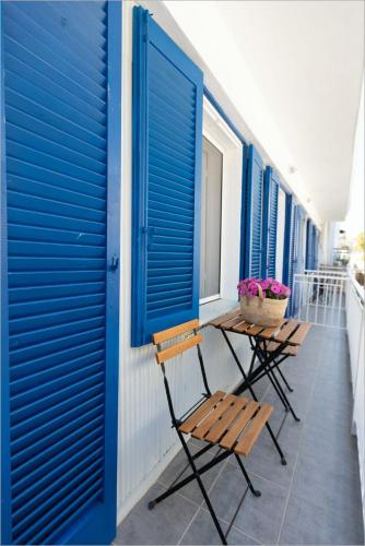 a row of chairs on a balcony with blue shutters at Ziv Boutique Apartments Town Square in Lefkada Town