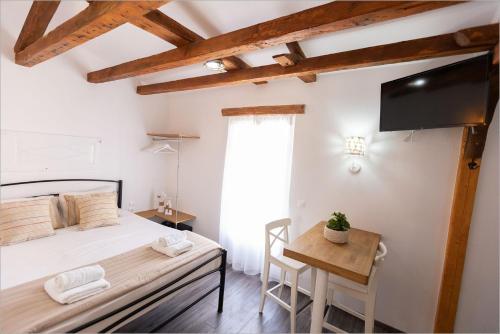 a bedroom with a bed and a desk and a tv at Ziv Boutique Apartments Town Square in Lefkada Town
