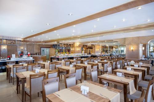 a restaurant with wooden tables and chairs and a bar at Porto Bello Hotel Resort & Spa in Antalya