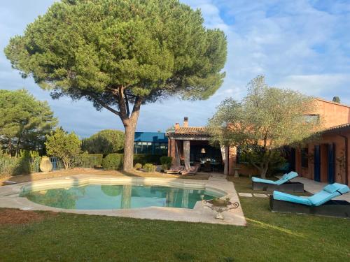 a pool in a yard with a tree and a house at L’Hacienda Francesa in Palaja