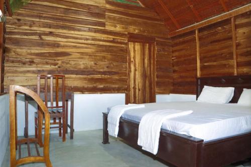 1 dormitorio con 1 cama y pared de madera en Ocean Breeze Resort, en Pottuvil