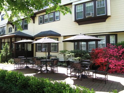 a group of tables and chairs with umbrellas in front of a house at Longwood Inn in Brookline