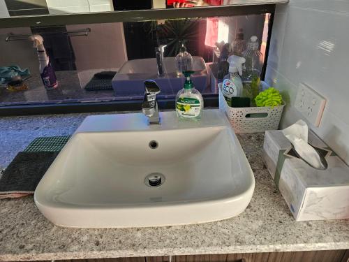 a bathroom sink with a bottle of soap on it at Private king bed guest suite in Perth
