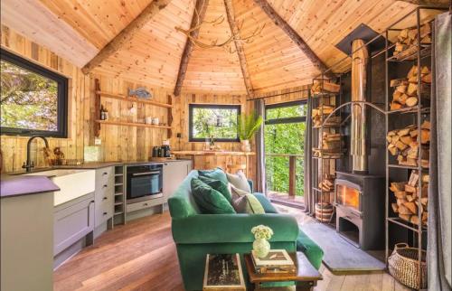 a kitchen and living room with a green couch at Unique Secluded Romantic Treehouse in Cornwall, sleeps 2 in Looe