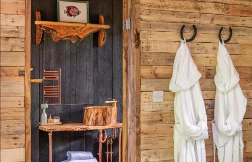 a bathroom with a wooden wall with a toilet and towels at Unique Secluded Romantic Treehouse in Cornwall, sleeps 2 in Looe