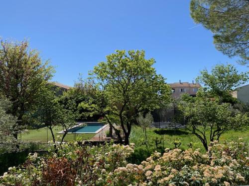 un jardin avec des arbres et une maison en arrière-plan dans l'établissement Appartement rez de chaussée maison indépendant avec piscine, à Saint-Christol-lès-Alès