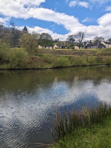 a body of water with a farm in the background at Cowslip Cottage Serenity with Jacuzzi in Saundersfoot