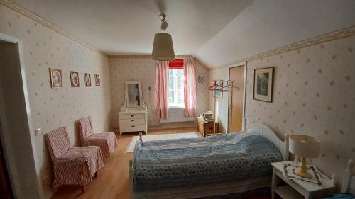 a bedroom with a bed and two chairs and a window at Förvaltarbostaden in Åtvidaberg