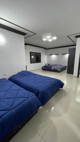 two beds in a room with blue sheets at aljazeera apartments in Amman