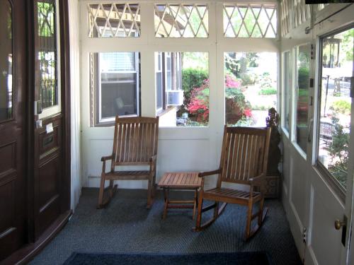 2 sillas y una mesa en una habitación con ventanas en Longwood Inn, en Brookline