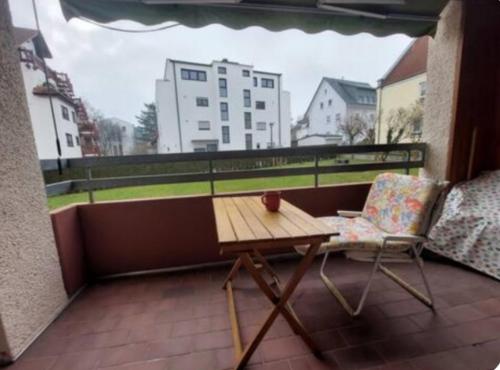 een balkon met een houten tafel en een stoel bij 1Room in a beautiful shared apartment 12min walk from Center in Friedrichshafen