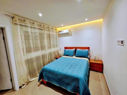 a bedroom with a blue bed and a window at Flamingo Plateau 1A apt on Rua Pedonal Praia Cape Verde in Praia