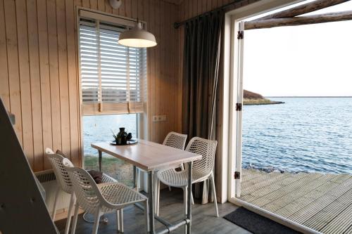 a table and chairs on a balcony with a view of the water at Brouwersdam Stay in Ouddorp