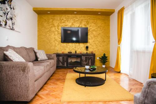 a living room with a couch and a tv on a wall at Čudna šuma apartmani Vrdnik in Vrdnik