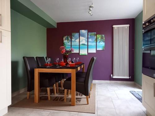 a dining room with a wooden table and black chairs at House with free parking and large garden in Wyke Regis