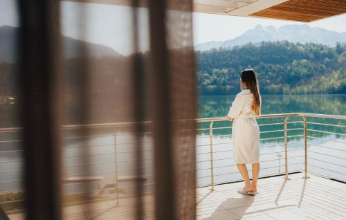 a woman standing on a balcony looking out at a lake at Parc Hotel Du Lac in Levico Terme