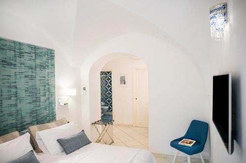 a bedroom with a bed and a blue chair at La Divina Amalfi Coast in Praiano