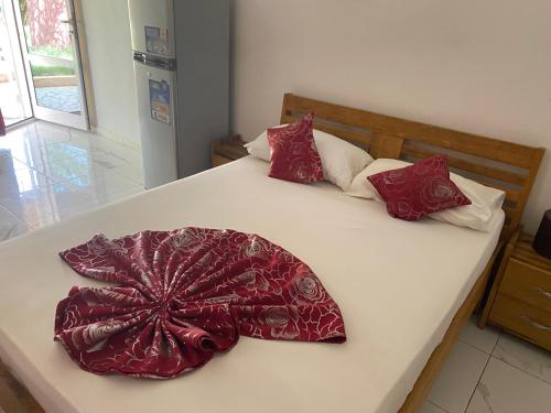 Una cama con almohadas rojas y blancas. en Le teranga royale lodge, en Nianing