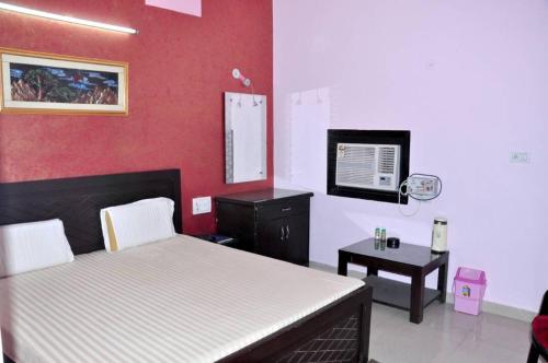 1 dormitorio con 1 cama, escritorio y TV en Hotel Tourist Bar & Restaurant, en Agra