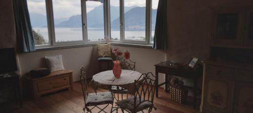 a dining room with a table and chairs and windows at La casa della Cindy in Dervio