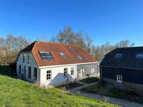 una casa bianca con un tetto arancione su una collina di Het Spoel a Culemborg
