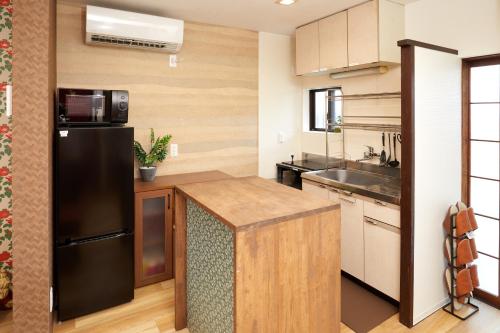 a kitchen with a black refrigerator and a sink at Walk to Nara Park-Nara's Timeless Stay in Nara