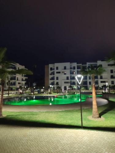 a green golf course with palm trees and buildings at Appartement costamar à 200m de la plage in Martil